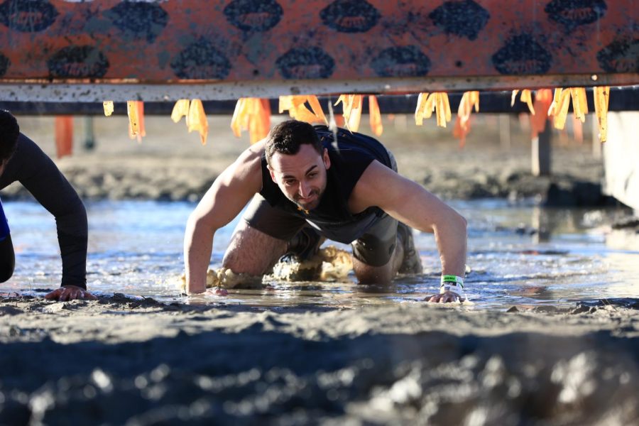 Jason Umansky crawls under barbed wire during Sundays Tough Mudder race.